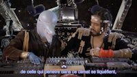a man and a woman are sitting at a table with a dj in front of them