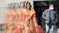 a woman in an orange dress walking down the street
