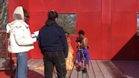 a group of people standing in front of a red building
