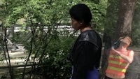 a woman is standing next to a tree in a park